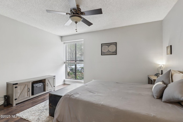 bedroom featuring baseboards, dark wood-type flooring, a ceiling fan, and a textured ceiling