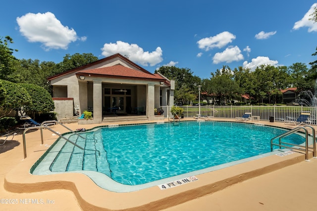 pool with a patio area and fence