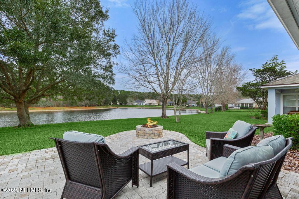 view of patio with a water view and an outdoor living space with a fire pit