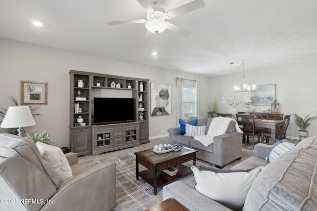 living room featuring wood-type flooring and ceiling fan with notable chandelier