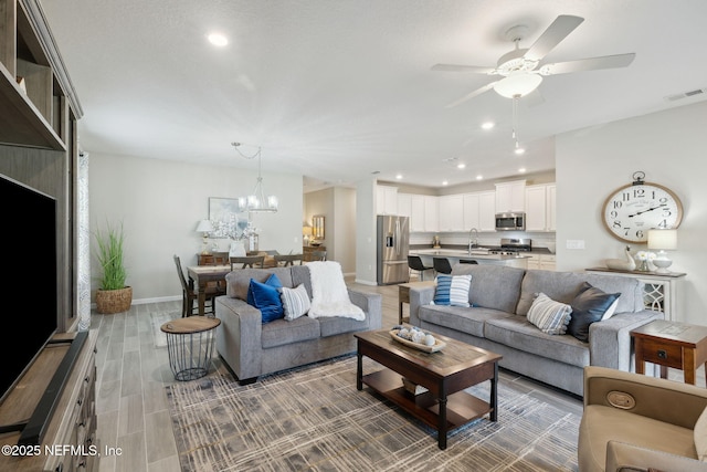 living room with sink, ceiling fan with notable chandelier, and hardwood / wood-style flooring