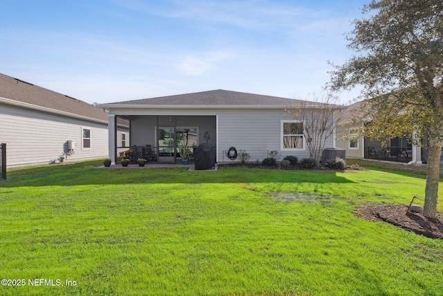 rear view of house featuring a sunroom, central air condition unit, and a lawn