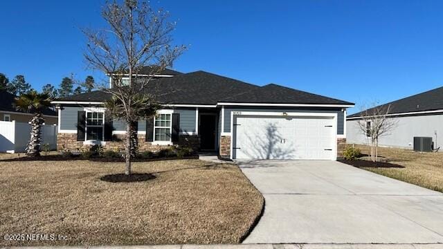 view of front of property with cooling unit, a front lawn, an attached garage, and driveway