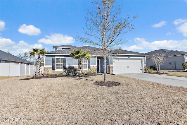 view of front of property with stone siding, concrete driveway, an attached garage, and fence