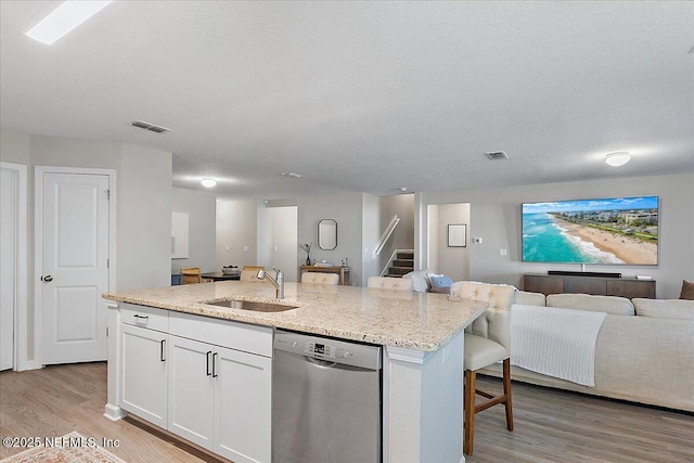 kitchen featuring visible vents, a sink, open floor plan, dishwasher, and a kitchen island with sink