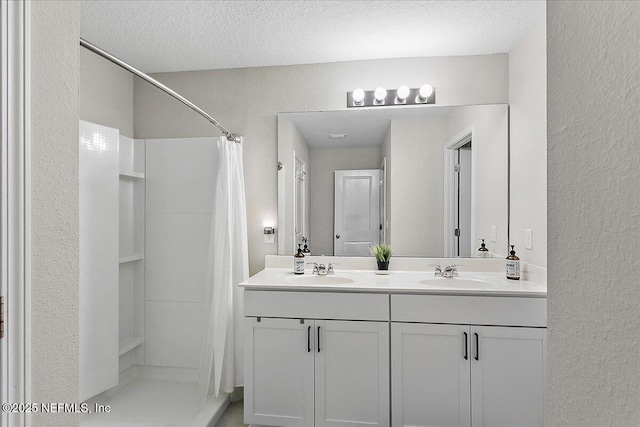 full bathroom featuring a sink, a textured ceiling, and double vanity