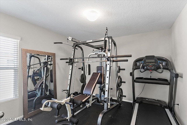 exercise room featuring a textured ceiling and baseboards