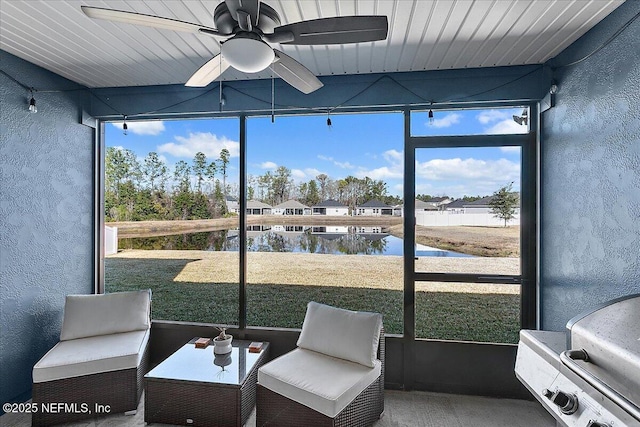 sunroom featuring a water view and ceiling fan