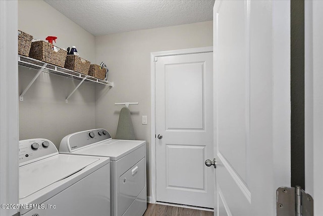 laundry area with wood finished floors, a textured ceiling, washing machine and dryer, and laundry area