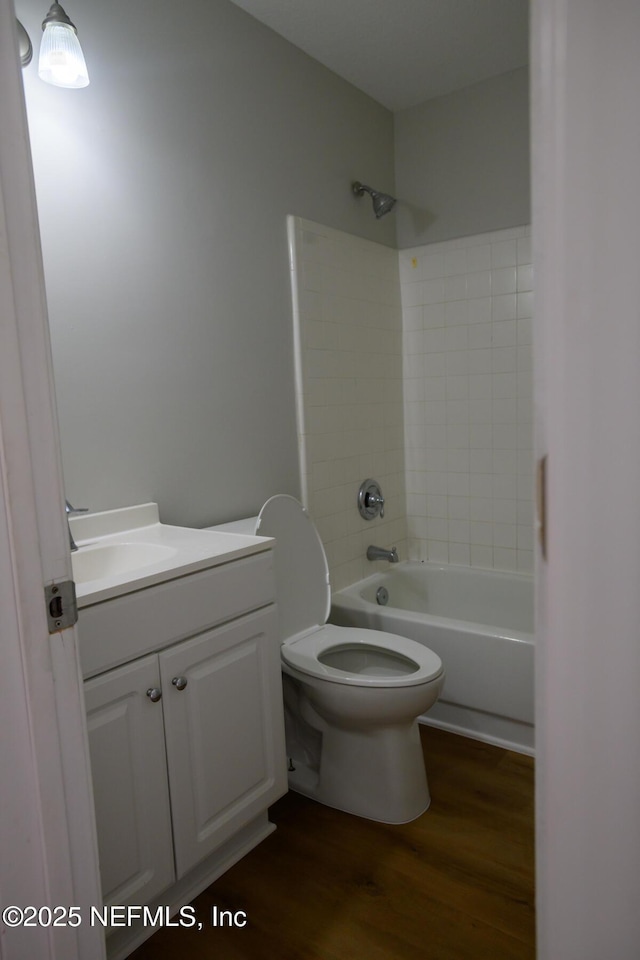 full bathroom featuring toilet, tiled shower / bath combo, hardwood / wood-style floors, and vanity