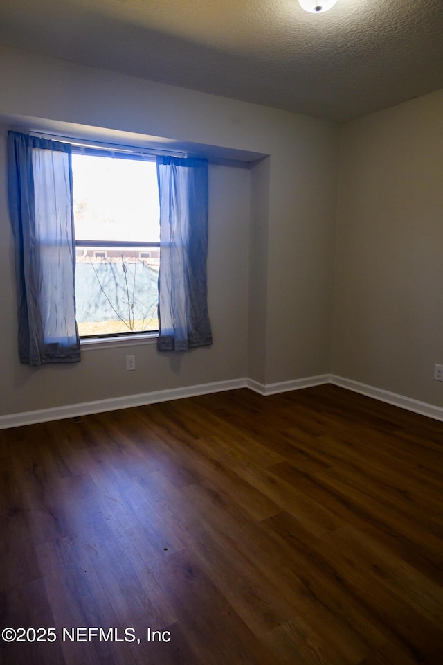 spare room with a textured ceiling and dark wood-type flooring