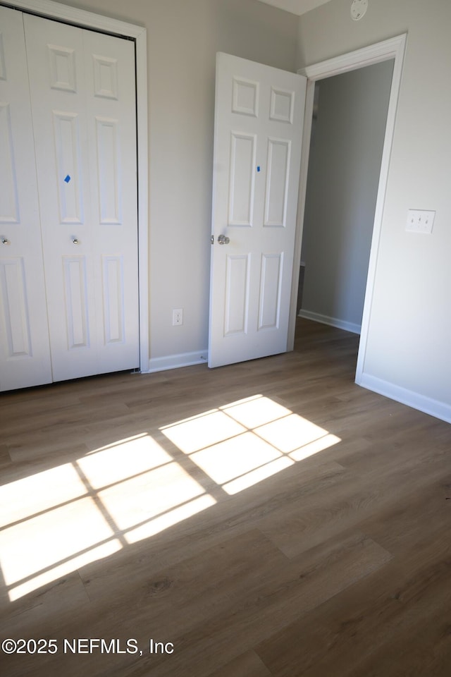 unfurnished bedroom with wood-type flooring and a closet