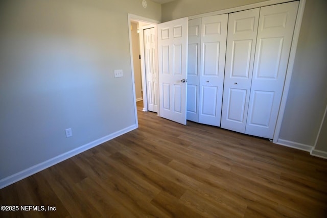 unfurnished bedroom featuring dark wood-type flooring and a closet