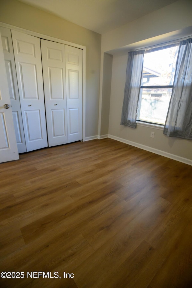 unfurnished bedroom with a closet and dark hardwood / wood-style flooring