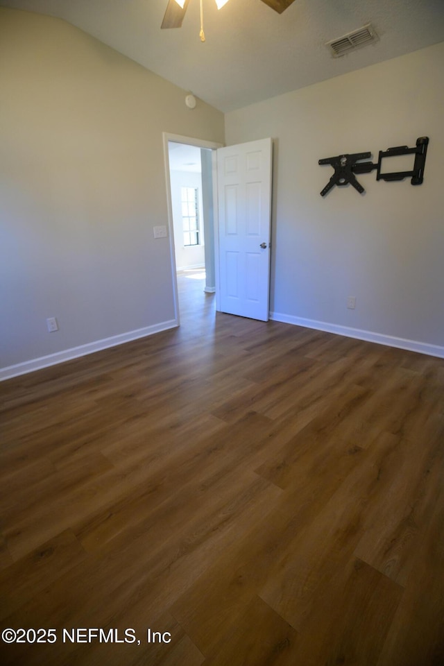 empty room with lofted ceiling, ceiling fan, and dark hardwood / wood-style floors