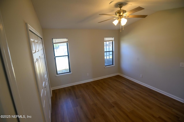 spare room with ceiling fan, vaulted ceiling, and dark wood-type flooring