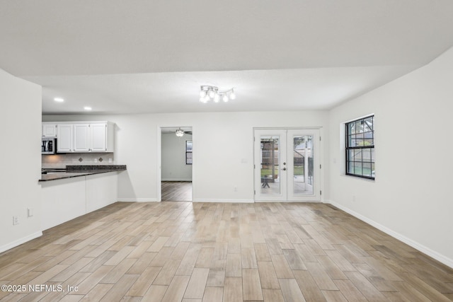 unfurnished living room featuring light hardwood / wood-style floors, french doors, and ceiling fan