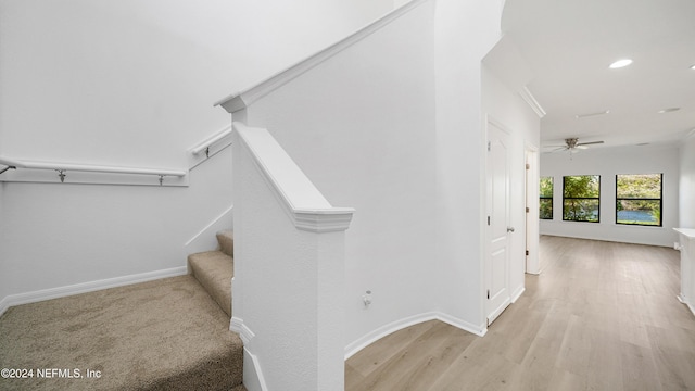 stairs featuring hardwood / wood-style floors, ceiling fan, and crown molding