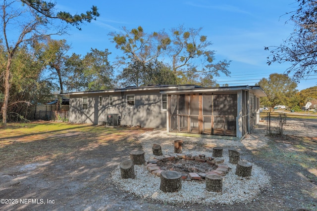 view of outbuilding with central AC, a sunroom, and an outdoor fire pit