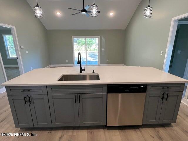 kitchen with lofted ceiling, sink, gray cabinets, dishwasher, and an island with sink