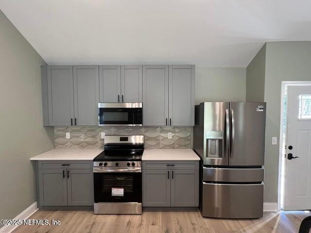 kitchen featuring gray cabinets, appliances with stainless steel finishes, and backsplash