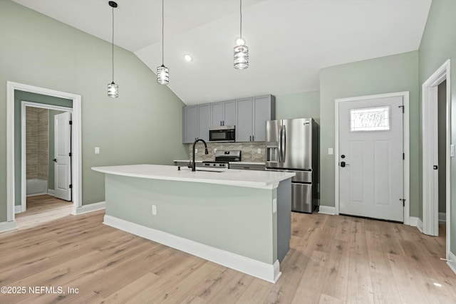 kitchen featuring pendant lighting, sink, gray cabinetry, a kitchen island with sink, and stainless steel appliances