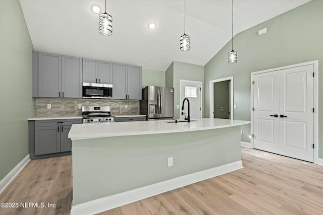 kitchen featuring stainless steel appliances, sink, a center island with sink, and gray cabinets