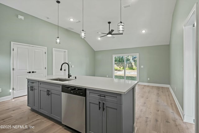 kitchen featuring stainless steel dishwasher, a kitchen island with sink, sink, and gray cabinetry