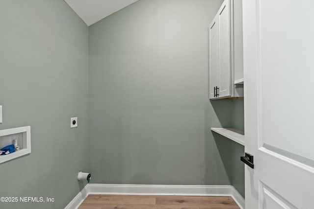 clothes washing area featuring electric dryer hookup, washer hookup, light hardwood / wood-style flooring, and cabinets