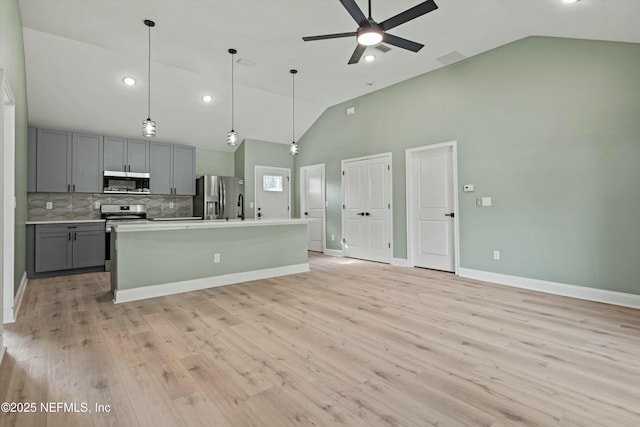 kitchen with appliances with stainless steel finishes, pendant lighting, gray cabinetry, a center island with sink, and light hardwood / wood-style flooring