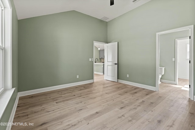 unfurnished bedroom with connected bathroom, high vaulted ceiling, and light hardwood / wood-style flooring