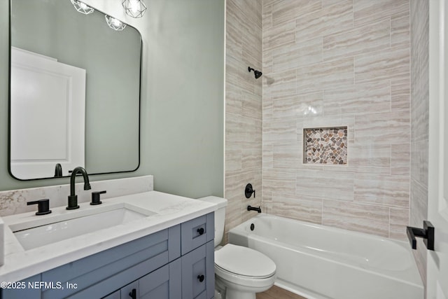 full bathroom featuring tiled shower / bath, vanity, and toilet