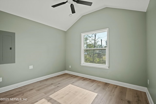 unfurnished room featuring ceiling fan, electric panel, vaulted ceiling, and light hardwood / wood-style flooring