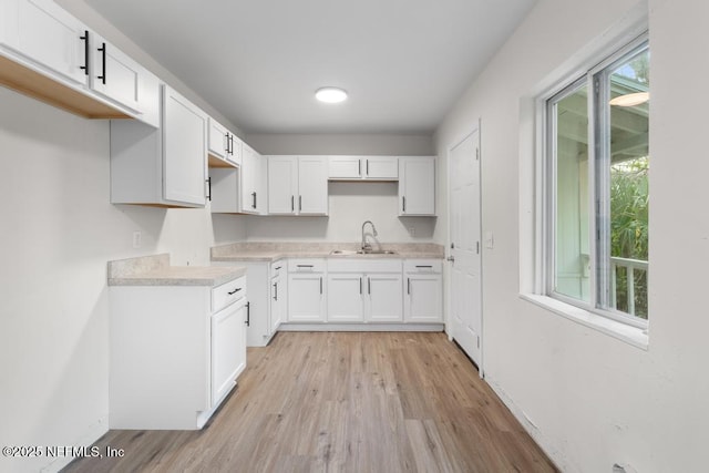 kitchen with white cabinetry, sink, and light hardwood / wood-style flooring