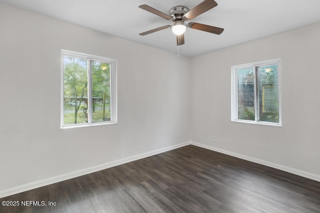 empty room with a wealth of natural light, ceiling fan, and dark wood-type flooring