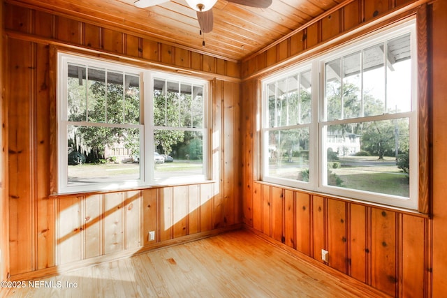 unfurnished sunroom with a healthy amount of sunlight, ceiling fan, and wooden ceiling