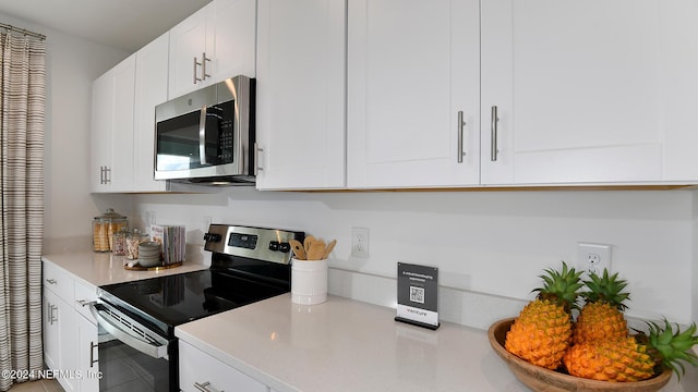 kitchen with tile patterned flooring, appliances with stainless steel finishes, and white cabinetry