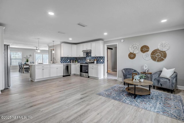 kitchen with kitchen peninsula, pendant lighting, white cabinetry, appliances with stainless steel finishes, and sink