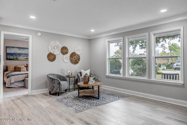 living area with ornamental molding and light hardwood / wood-style flooring