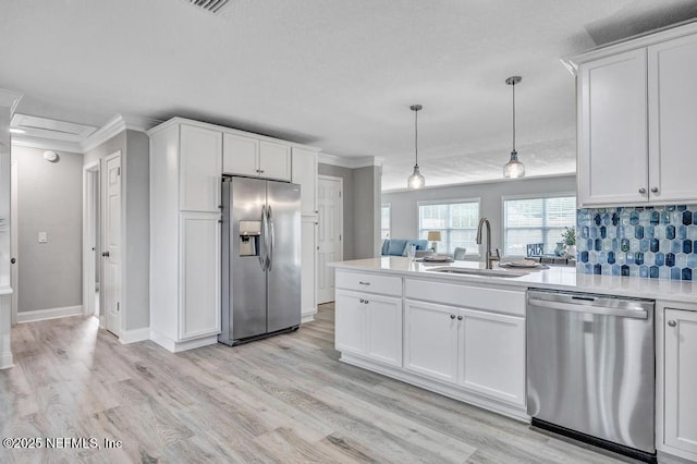 kitchen featuring hanging light fixtures, backsplash, white cabinetry, appliances with stainless steel finishes, and sink