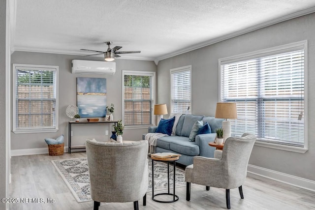 sitting room featuring an AC wall unit, ceiling fan, ornamental molding, hardwood / wood-style flooring, and a textured ceiling