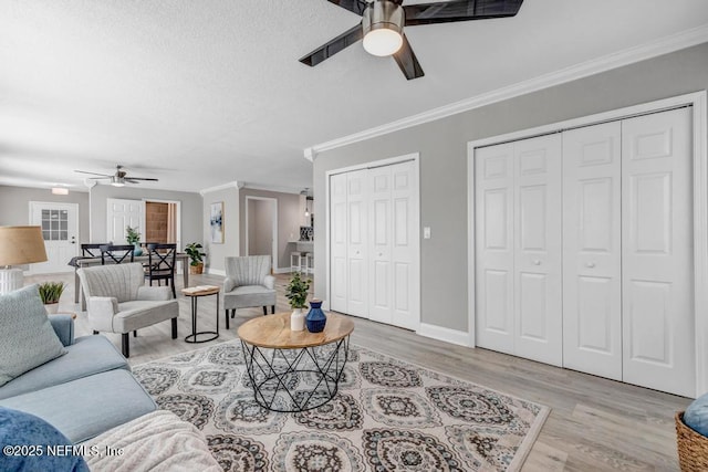 living room with ceiling fan, ornamental molding, and light hardwood / wood-style floors