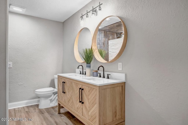 bathroom with toilet, a textured ceiling, vanity, and hardwood / wood-style floors