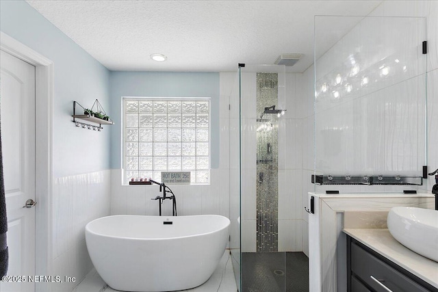 bathroom with tile walls, vanity, a textured ceiling, tile patterned floors, and shower with separate bathtub