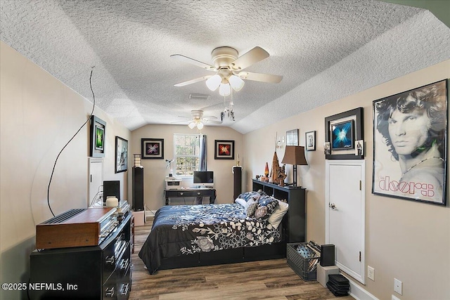 bedroom featuring dark wood-type flooring, a textured ceiling, vaulted ceiling, and ceiling fan