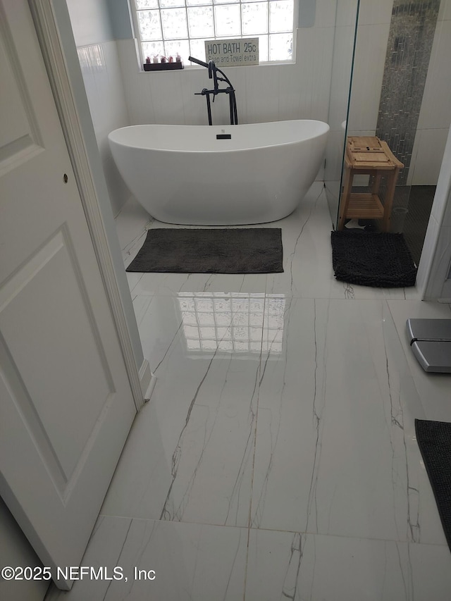 bathroom with tile patterned flooring, a washtub, and tile walls