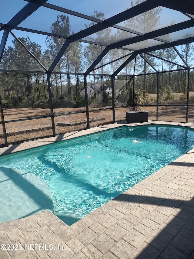 view of swimming pool featuring pool water feature, glass enclosure, and a patio area