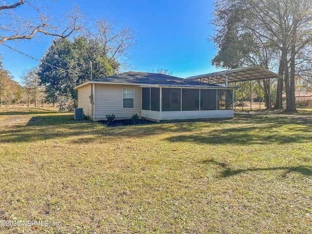 rear view of house featuring a carport, central AC unit, a yard, and a sunroom