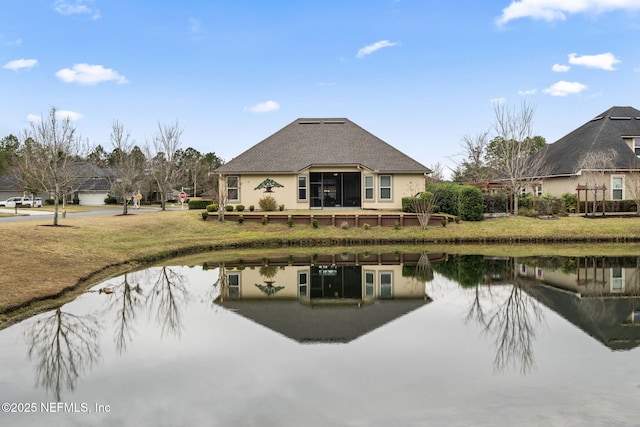 rear view of house featuring a lawn and a water view