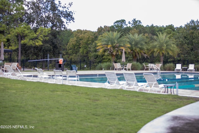 community pool featuring a patio area, fence, and a lawn